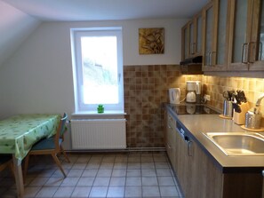 Eine kleine Küche mit Fenster, Heizkörper, Kaffeemaschine und Spüle.