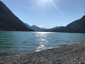 En sjö med en stenig strand och berg i bakgrunden.