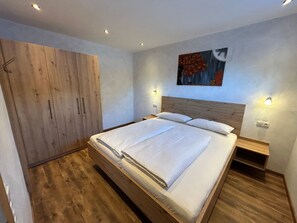 A bedroom with a wooden bed, a wardrobe, and a painting on the wall. - Barbara by Interhome (Bichlbach)