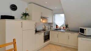 Een moderne keuken met witte kastjes, een houten eettafel en een magnetron.