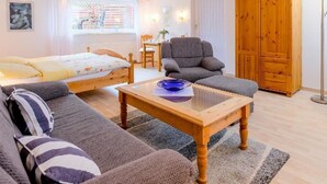 En hyggelig stue med en seng, sofa, træbord og garderobe.