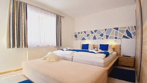 Ein Hotelzimmer mit einem großen Bett, einem Nachttisch, einer Lampe und einem Fenster mit Vorhängen.