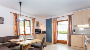 Eine moderne Küche mit Holzausstattung, ein Essbereich mit Tisch und Stühlen sowie ein Fernseher.