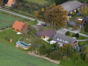 An aerial view of a residential area with houses, a road, and a large tree. - Blockhaus für fünf Personen by Interhome (Sudwalde)