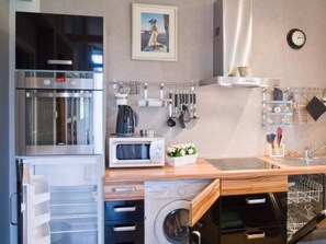 Eine moderne Küche mit Edelstahlgeräten, einer Mikrowelle, einer Kaffeemaschine und einem Küchenutensilienhalter.