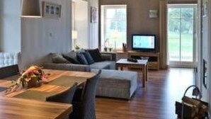 A spacious living room with a wooden floor, a large sofa, a coffee table, and a television. - Apartment Abendsonne mit eigener Terrasse by Interhome (Klein Meckelsen)