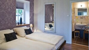 A bedroom with a double bed, a mirror, a window, and a bathroom visible through an open door. - Apartment Abendsonne mit eigener Terrasse by Interhome (Klein Meckelsen)
