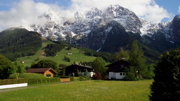A mountain landscape with snow-capped peaks, a clear sky, and a green valley with houses. - Apartment Bergblick by Interhome (Abtenau)