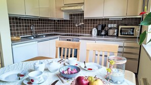A kitchen with a dining table set for two, a microwave, and a kettle. - Apartment Bergblick by Interhome (Abtenau)