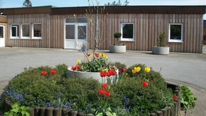 Een gebouw met een houten gevel, grote ramen en een bloembed met rode en gele tulpen.