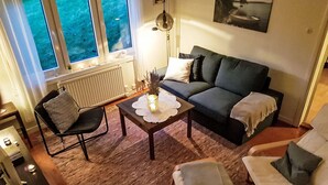 A cozy living room with a sofa, two armchairs, a coffee table, and a window with a view of greenery. - Villa Bullerbü by Interhome (Norrhult)