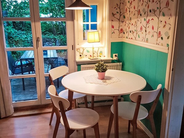 A dining area with a round table, four chairs, a potted plant, and a lamp.