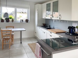 Une cuisine moderne avec des meubles blancs, une table à manger en bois et des chaises.