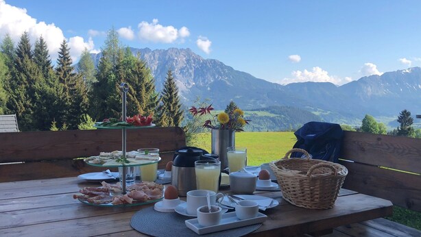 Mesa de piquenique montada com comida e bebidas, com vista para uma paisagem montanhosa.