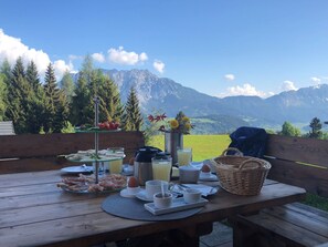 Une table de pique-nique dressée avec de la nourriture et des boissons, offrant une vue sur un paysage montagneux.