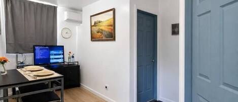 Una habitación con un escritorio, computadora y un cuadro en la pared.