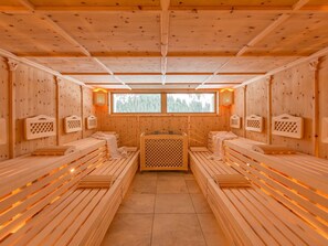 Sala de sauna com bancos de madeira e unidade de aquecimento central.