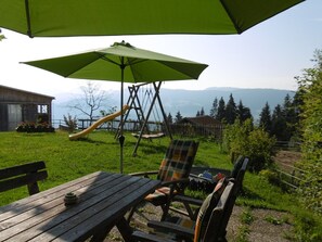 A patio with a wooden table and chairs, a swing set, and a view of mountains. - Friesenhof Blank in Sulzberg by Interhome (Sulzberg)