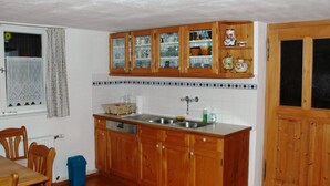 A kitchen with wooden cabinets, a sink, and a window with curtains. - Dünser in Dünserberg by Interhome (Dünserberg)