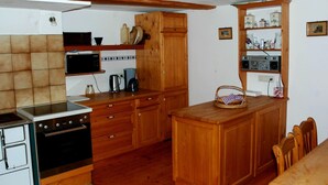 A compact kitchen with wooden cabinets, a built-in oven, a microwave, and a coffee maker. - Dünser in Dünserberg by Interhome (Dünserberg)