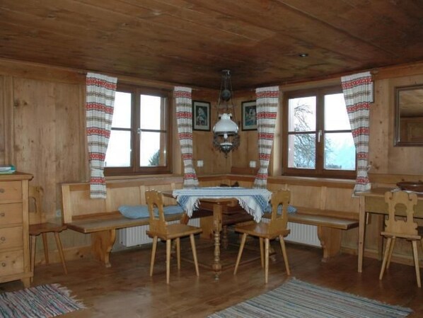 Una cabaña de madera con una mesa central, dos bancos de madera y un radiador.