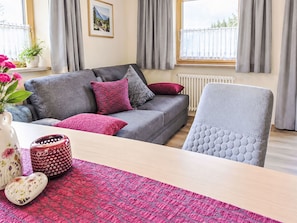 A modern living room with a grey sofa, red and grey cushions, a white armchair, a wooden coffee table, and a patterned rug. - in Wildermieming by Interhome (Wildermieming)