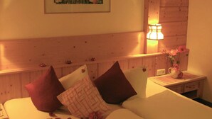 Een hotelkamer met een houten hoofdeinde, een nachtkastje met een lamp en een bloemstuk.