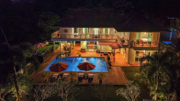 Ein zweistöckiges Haus mit Swimmingpool, Sitzgelegenheit im Freien und einem Balkon.