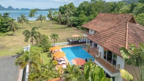 Ein Resort mit Schwimmbad, Liegestühlen und Blick aufs Meer.