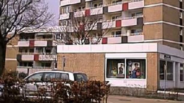 Un edificio a più piani con facciata uniforme, caratterizzato da una serie di balconi e un ingresso a livello strada.