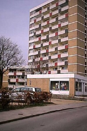 A multi-story building with a uniform facade, featuring a series of balconies and a ground-level entrance.