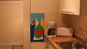 Una cucina compatta con forno a microonde, macchina del caffè, tostapane e lavello.