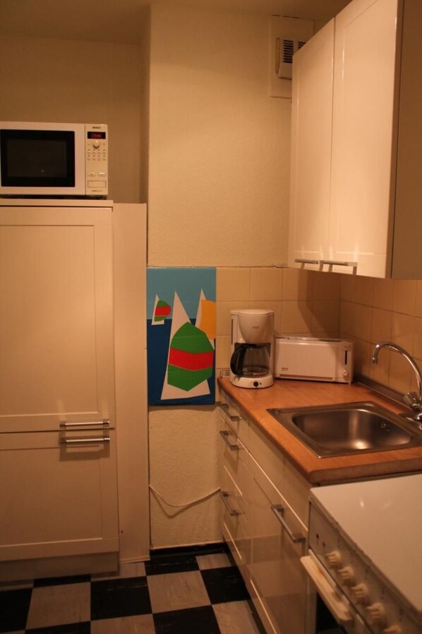 A compact kitchen with a microwave, coffee maker, toaster, and sink.