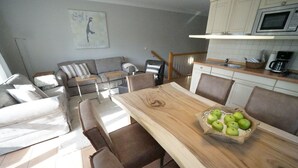 Una cocina moderna con una mesa de comedor de madera, un frutero y un sofá gris en la sala.