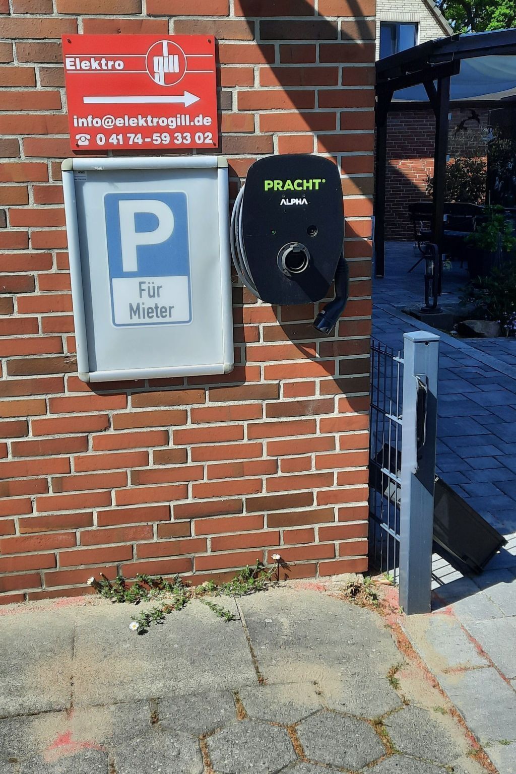 A brick building with a parking sign, a mailbox, and a solar panel.