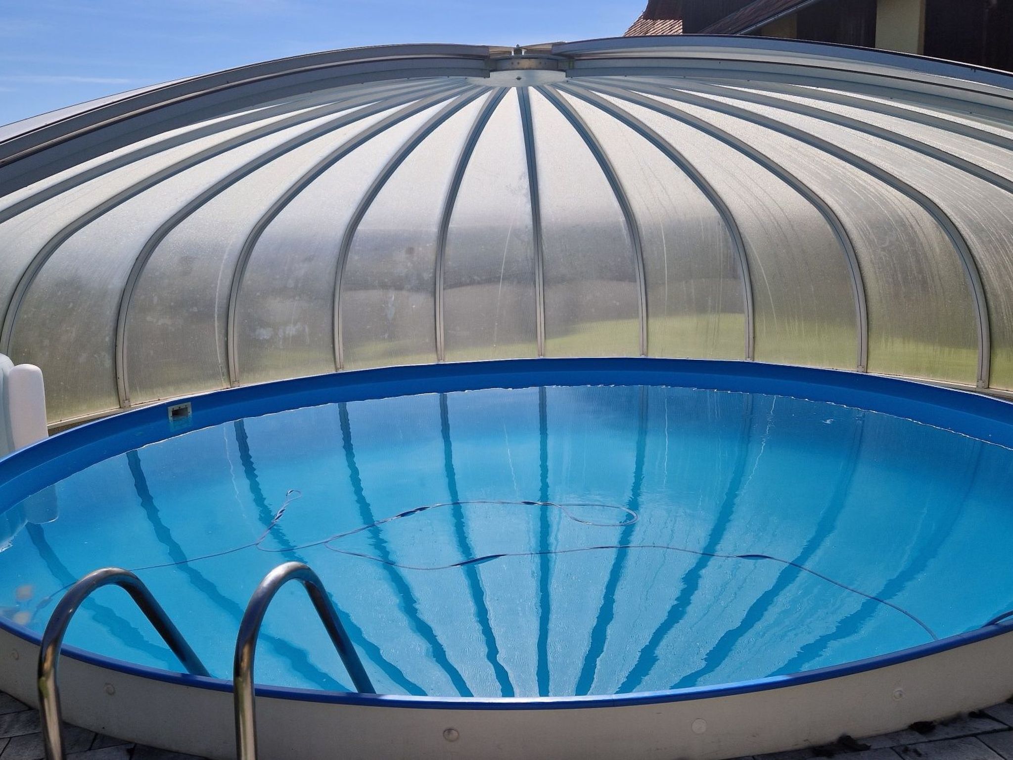 A covered swimming pool with a blue interior and a metal ladder.