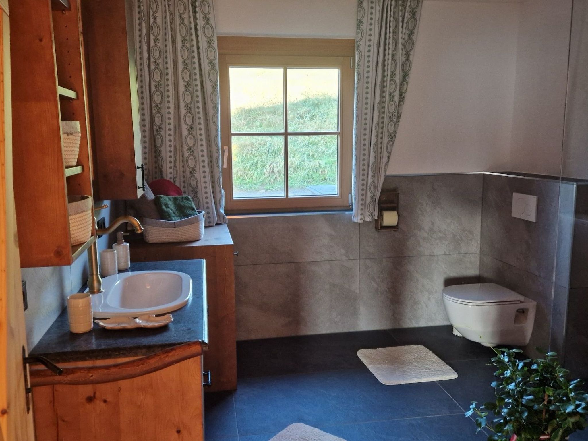 Bagno con lavandino, wc e finestra con tende.
