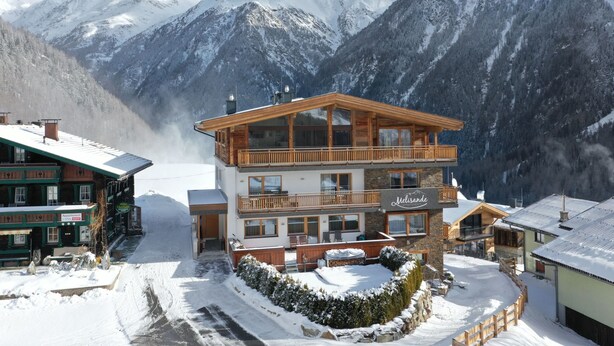 A two-story hotel with a wooden balcony, a hot tub, and a view of snow-covered mountains. - The Peak Sölden by Interhome (Sölden)