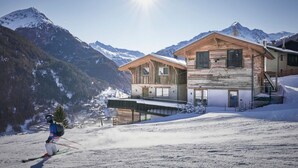A modern ski resort with wooden cabins, a ski slope, and snow-covered mountains in the background. - The Peak Sölden by Interhome (Sölden)