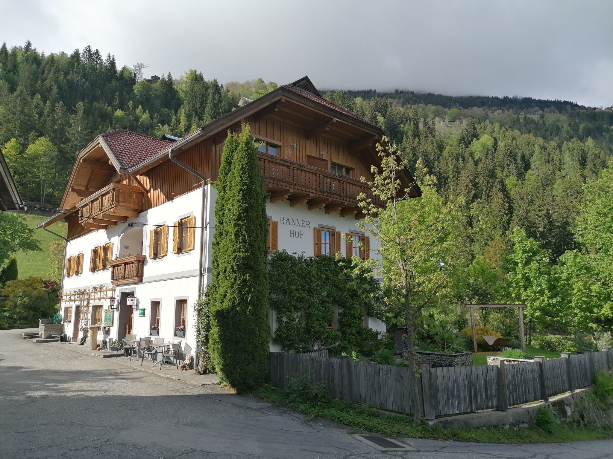 Ein traditionelles Chalet mit Balkon, gelegen in einer bewaldeten Gegend mit Blick auf die umliegenden Hügel.