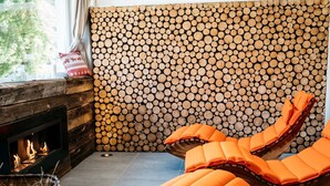 Ein gemütlicher Raum mit Kamin, einer Holzwand und zwei orangefarbenen Sesseln.