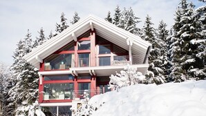 Ein mehrstöckiges Gebäude mit roter und weißer Fassade, großen Fenstern und einem Balkon.