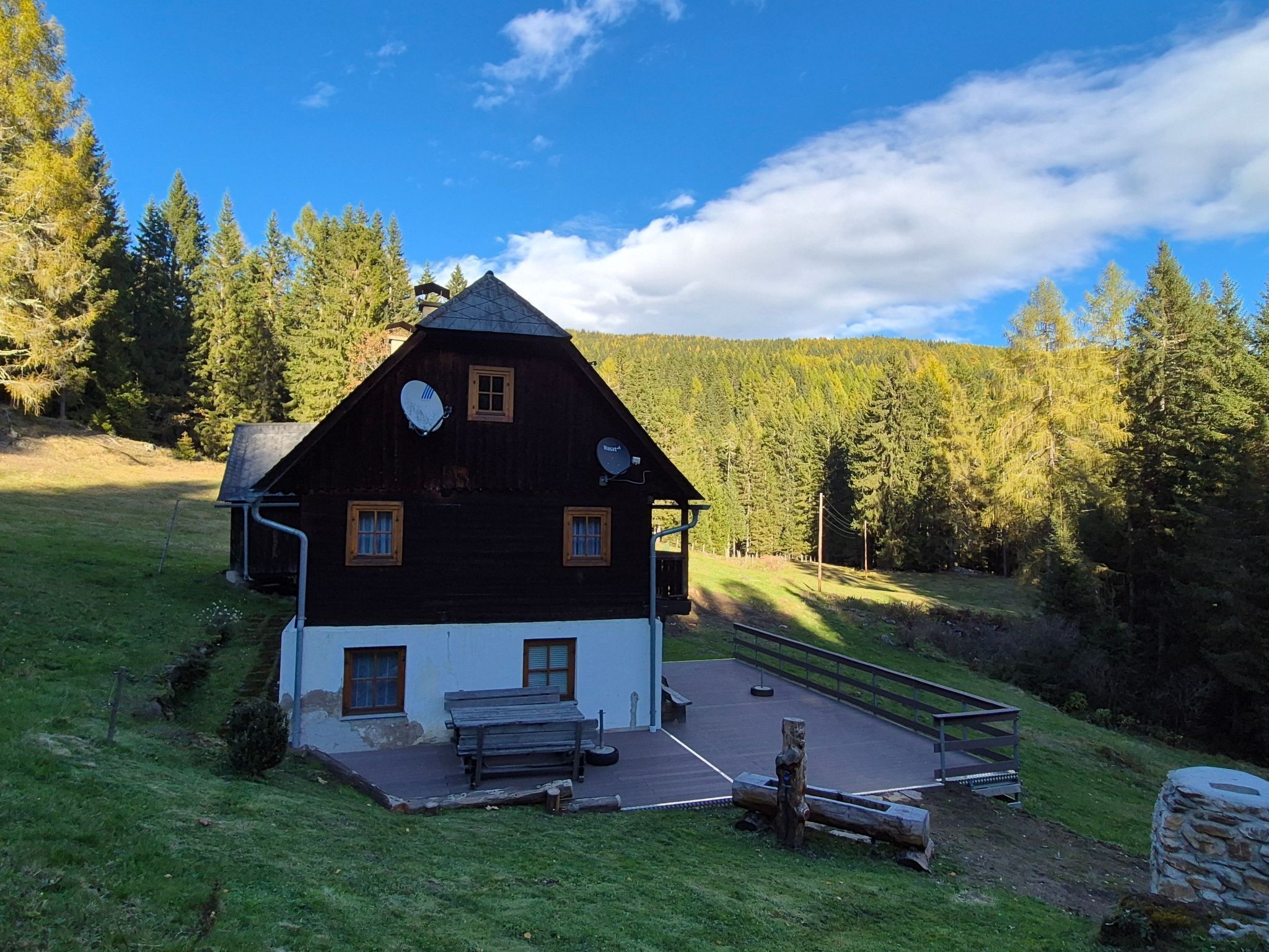 Une maison en bois avec un toit en pente, un petit porche et une antenne parabolique.