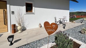 Ein weißes Gebäude mit einem herzförmigen Schild, auf dem 'Herzlich Willkommen' steht, und einem kleinen Fenster.