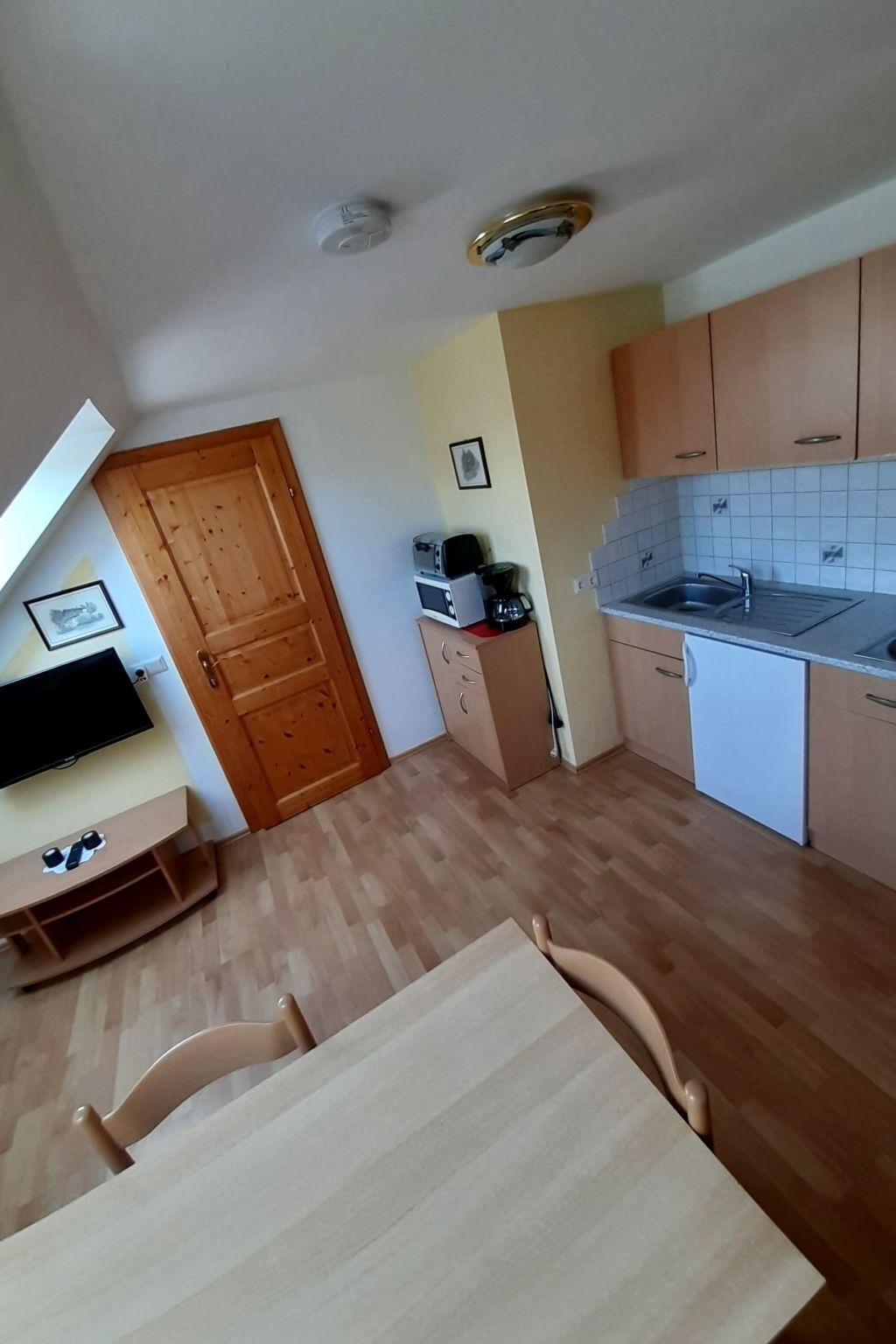 A compact kitchen with wooden cabinets, a built-in dishwasher, and a small countertop.