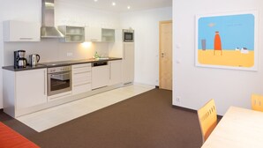 A modern kitchen with white cabinets, stainless steel appliances, and a wooden door. - Bohemia 3 in Gargellen by Interhome (Gargellen)