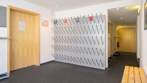 A hallway with a wall-mounted coat rack, a wooden door, and a fire extinguisher. - Bohemia 3 in Gargellen by Interhome (Gargellen)