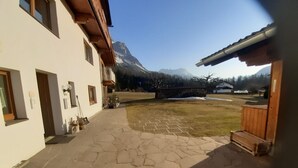 A stone-paved courtyard with a wooden bench, a small garden, and a mountain backdrop. - Ehrwalder Sonnenhof by Interhome (Ehrwald)