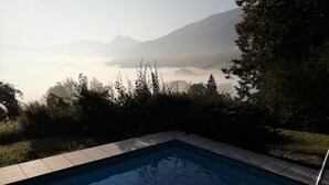 Una piscina con vistas a montañas y una zona boscosa.
