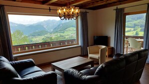 Una sala de estar con vista a montañas, una araña y un televisor.